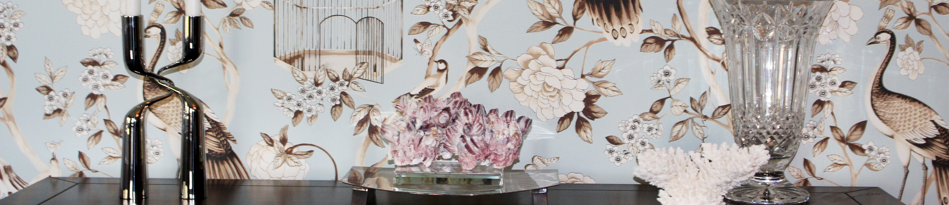 A collection of modern art pieces arranged in front of floral wallpaper