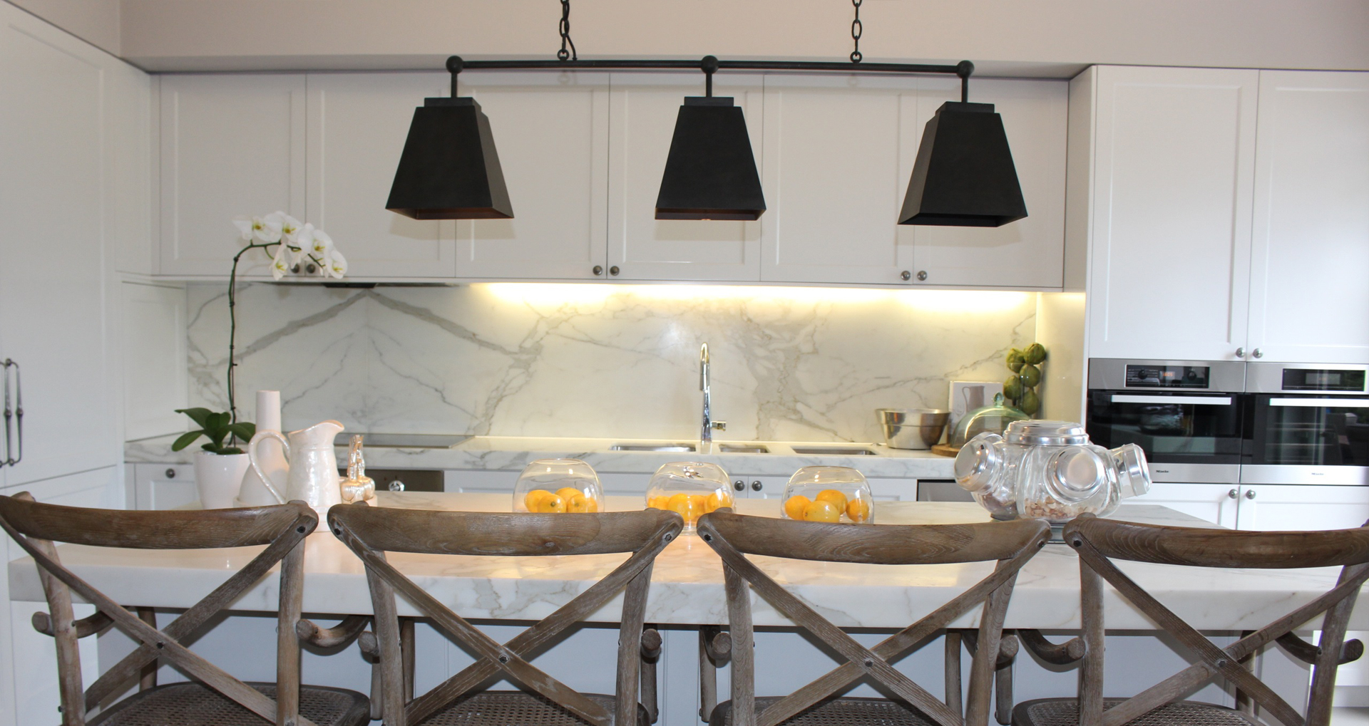 A modern kitchen with fruit bowls and a spice rack on the counter